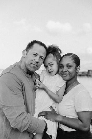 A close-knit family embraces while posing for photos by the ocean.