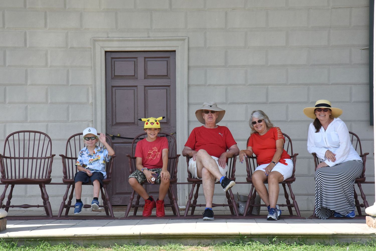 Group of people relaxing in rocking chairs on a porch.