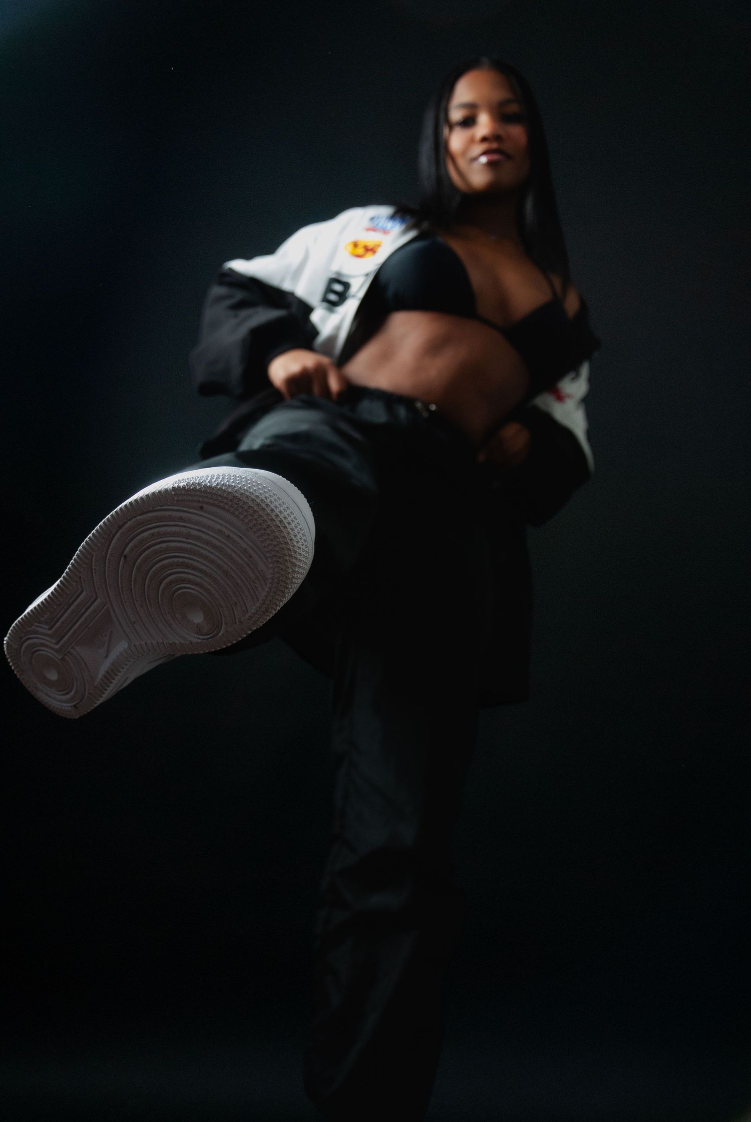 Artistic low-angle portrait showcasing urban streetwear fashion and sneakers against dark background.