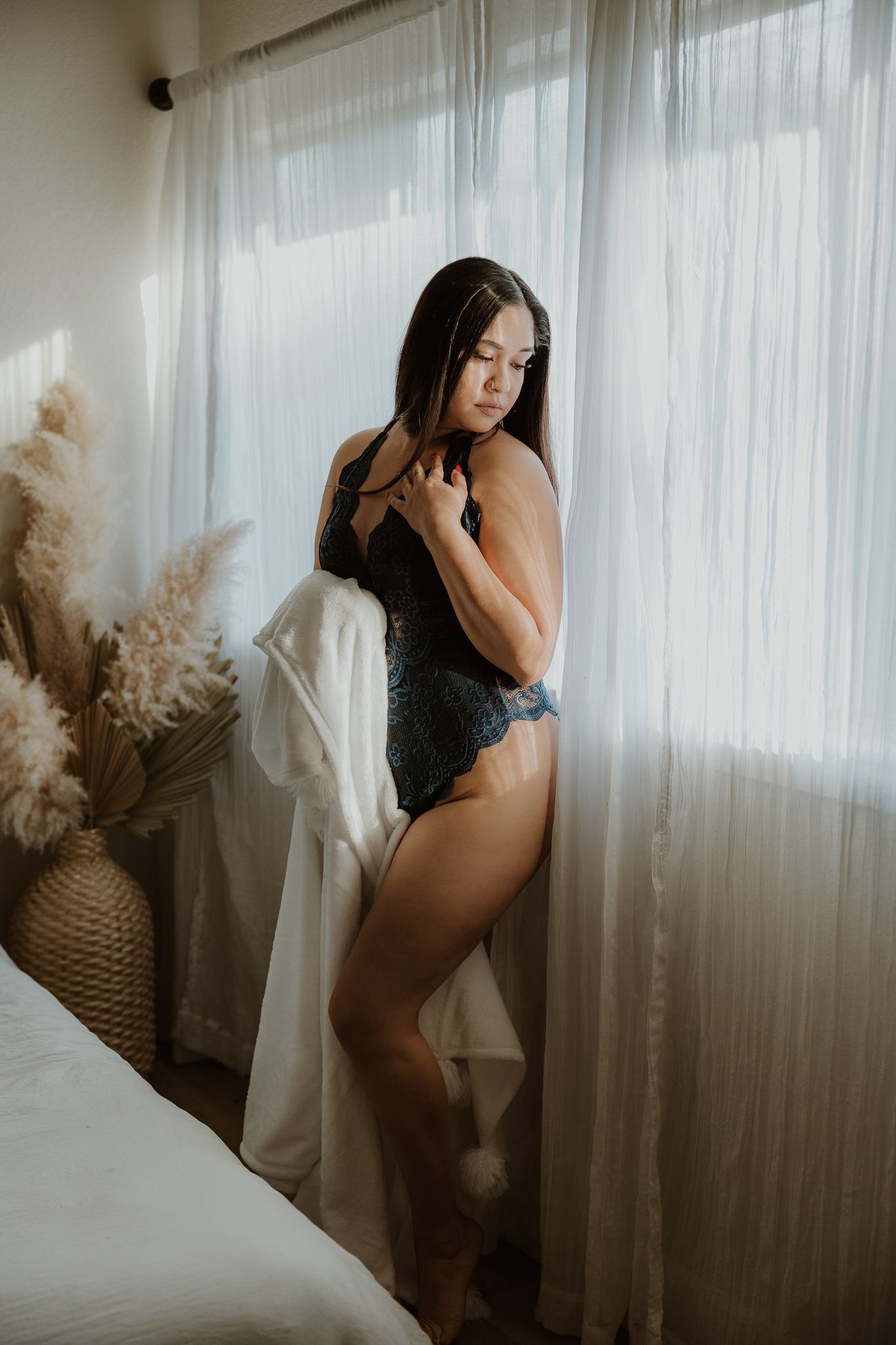 Artistic boudoir portrait with natural window light and pampas grass decoration.