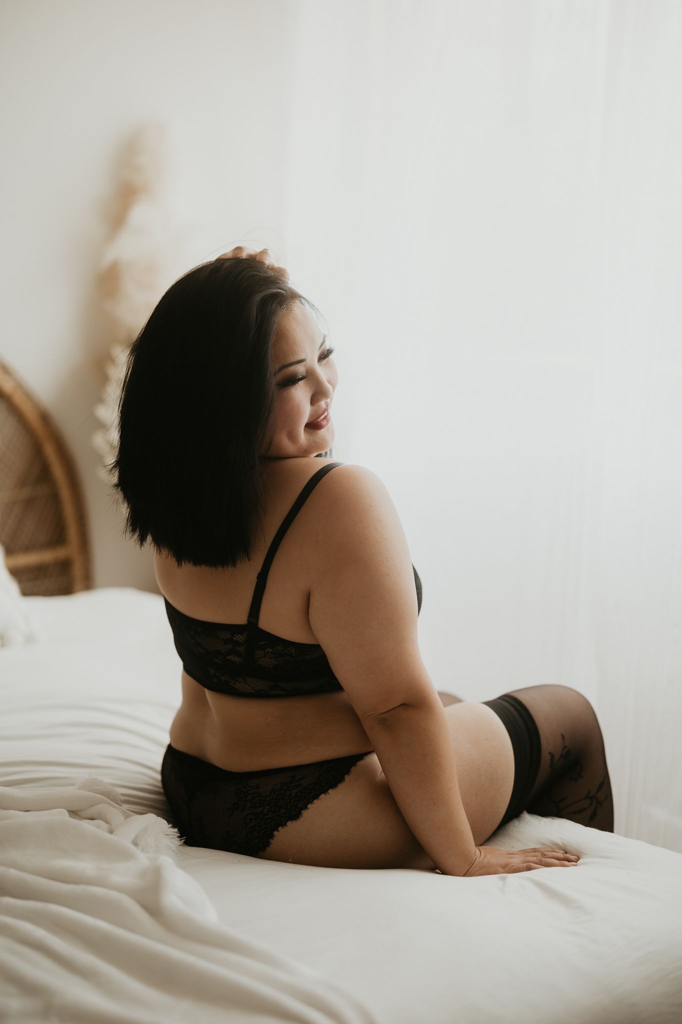 Intimate portrait session on white bedding with natural lighting.