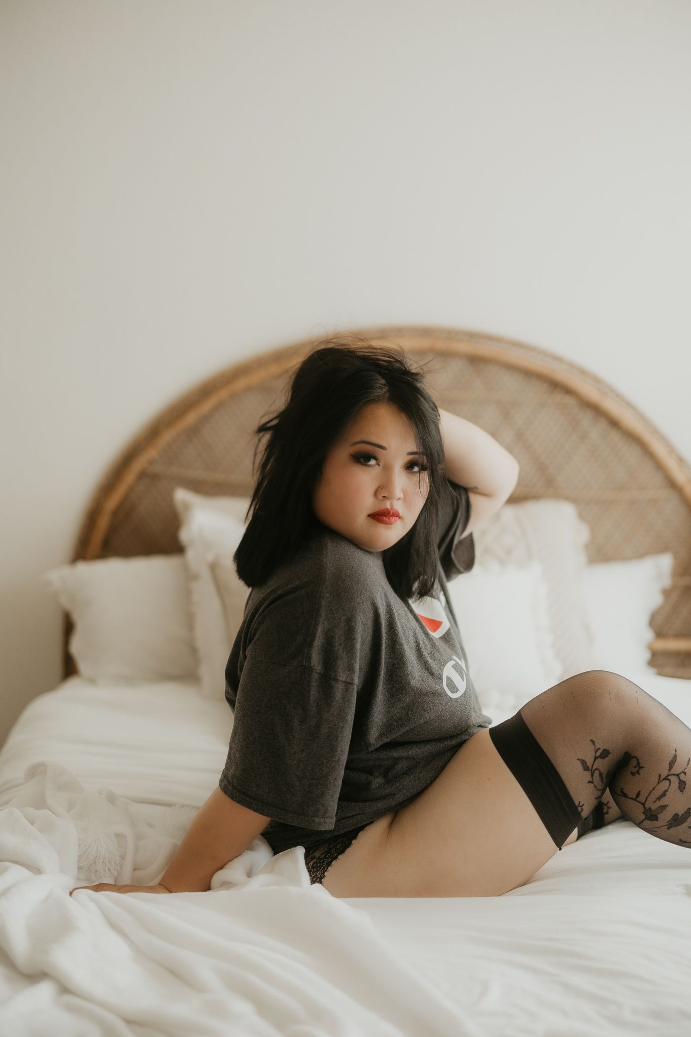 Intimate portrait of woman wearing oversized t-shirt on bed.