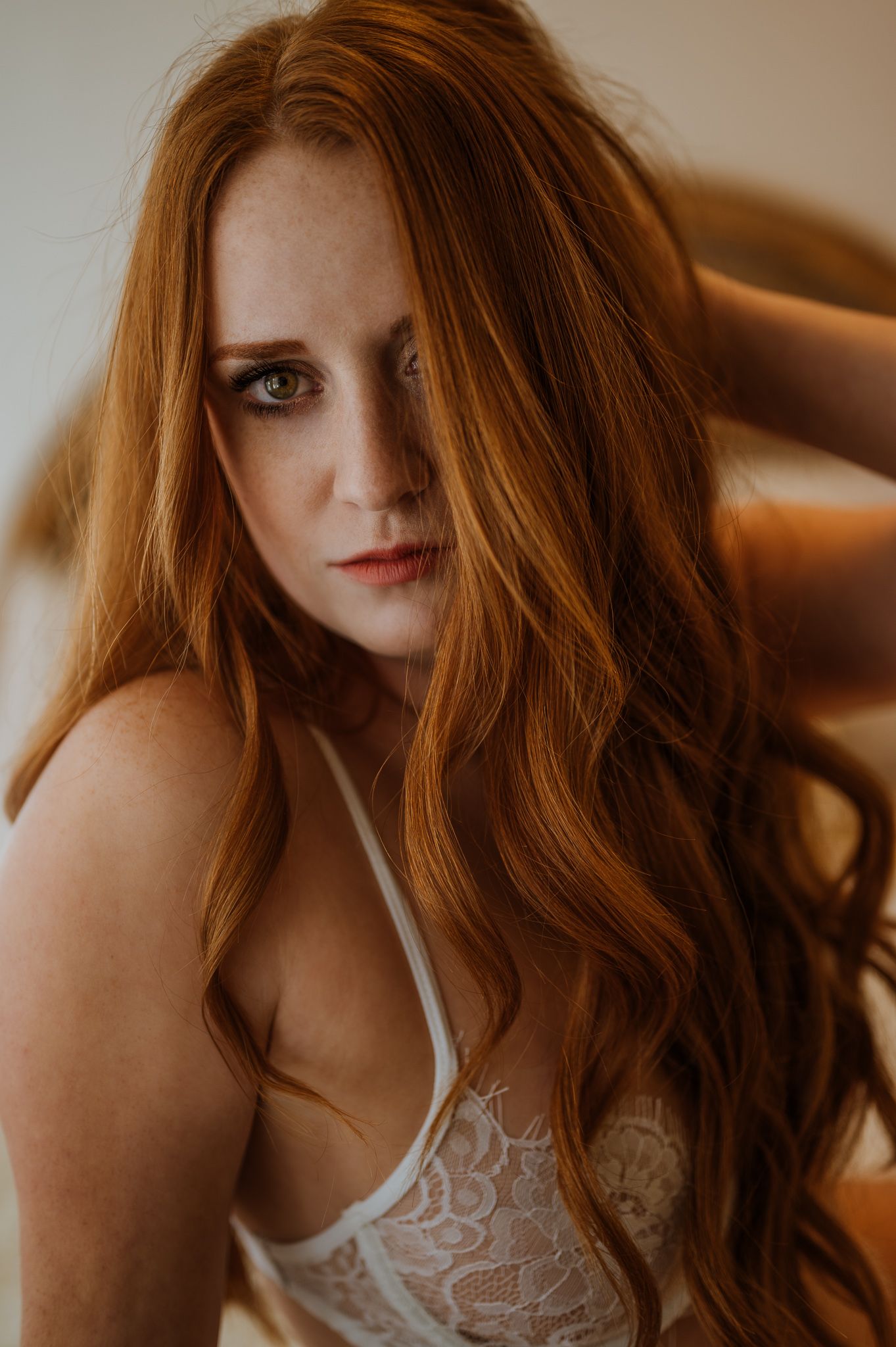 Portrait of person with flowing red hair wearing white lace lingerie.