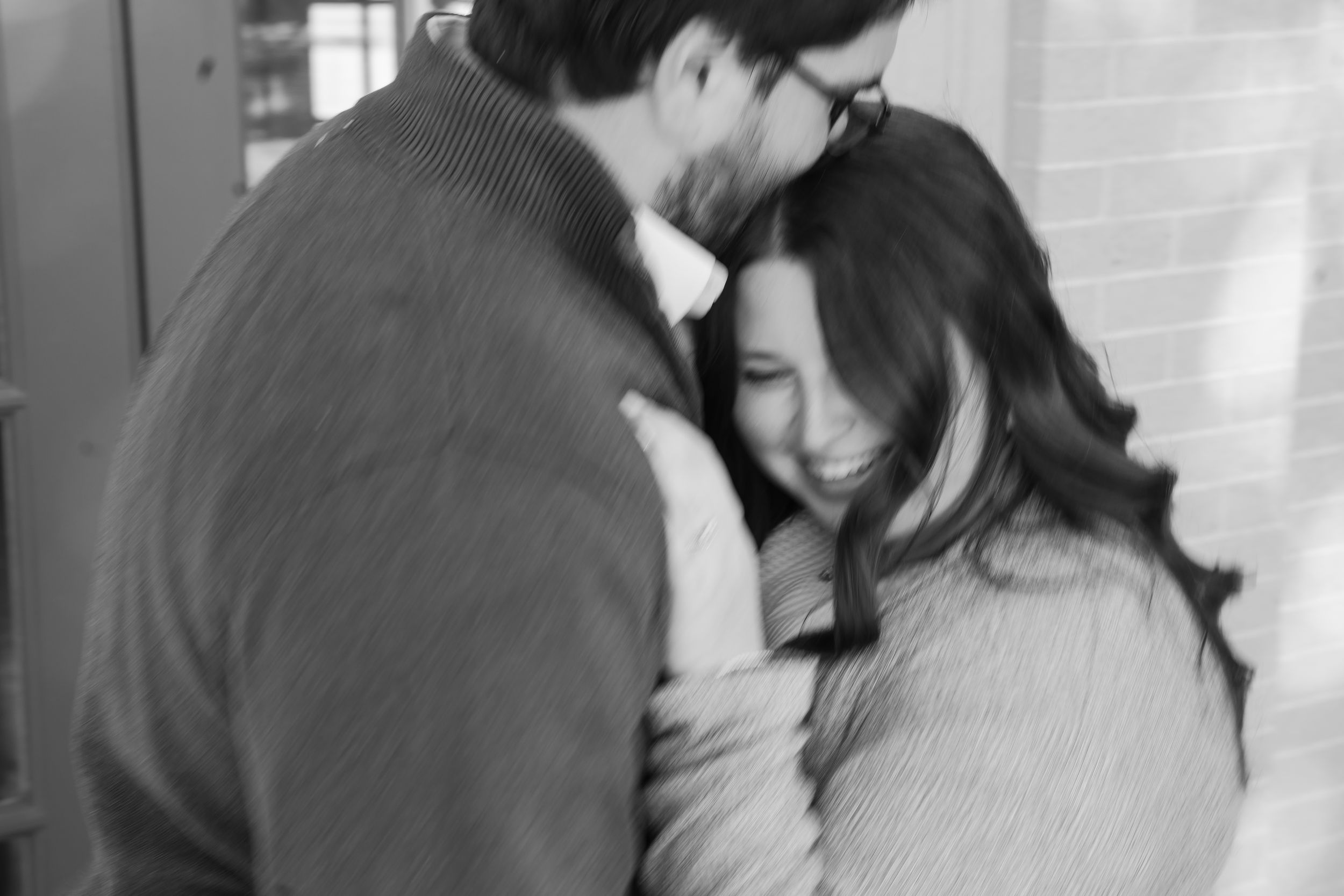 a blurry black and white image of a couple hugging and laughing