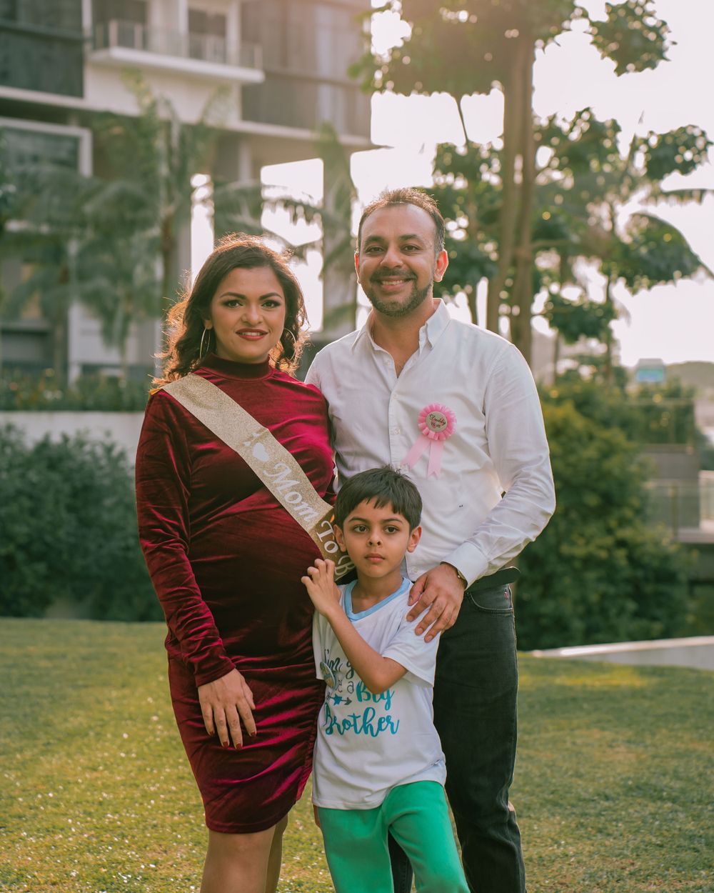 A family poses outdoors with a modern building in the background during sunset.
