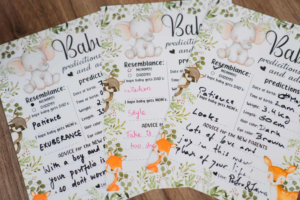 Multiple woodland-themed baby shower game cards spread out on wooden table surface.