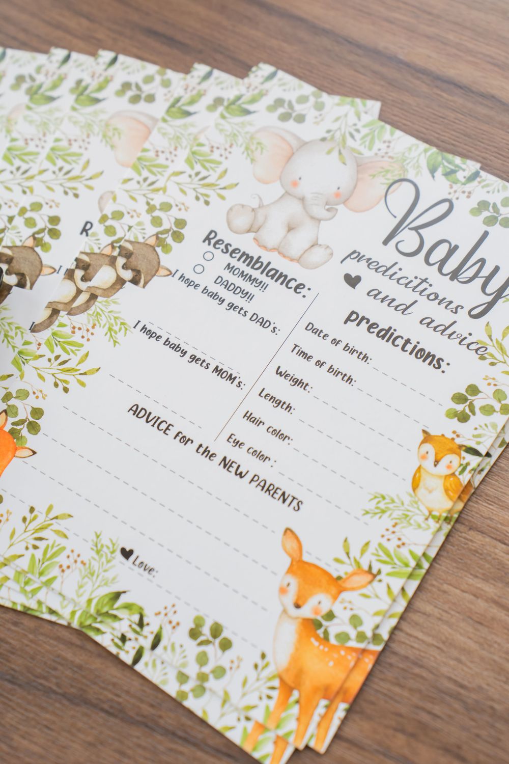 Woodland-themed baby shower game cards with fox and deer illustrations on a wooden surface.