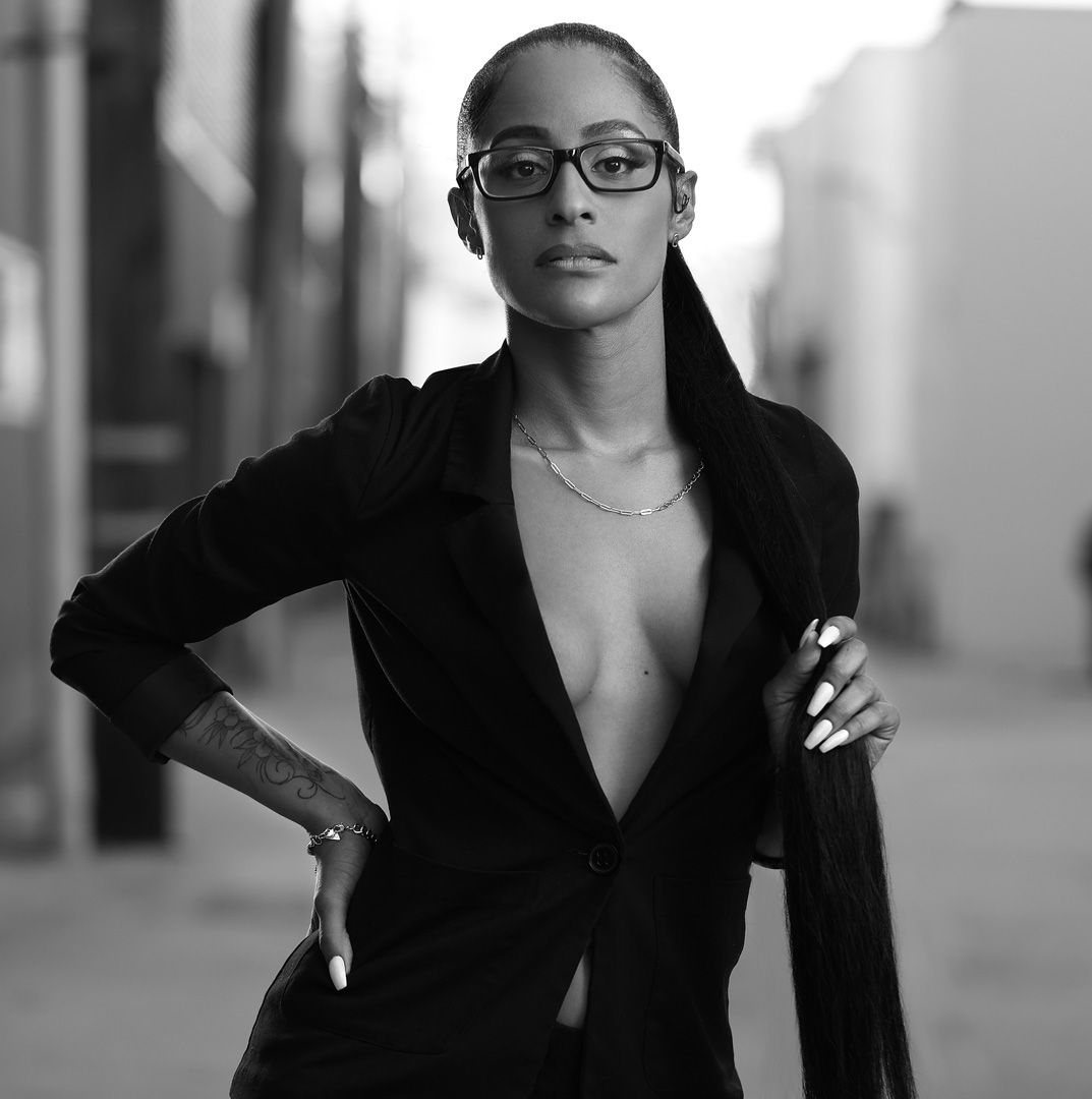 Professional black and white portrait of a person in glasses wearing a black blazer.