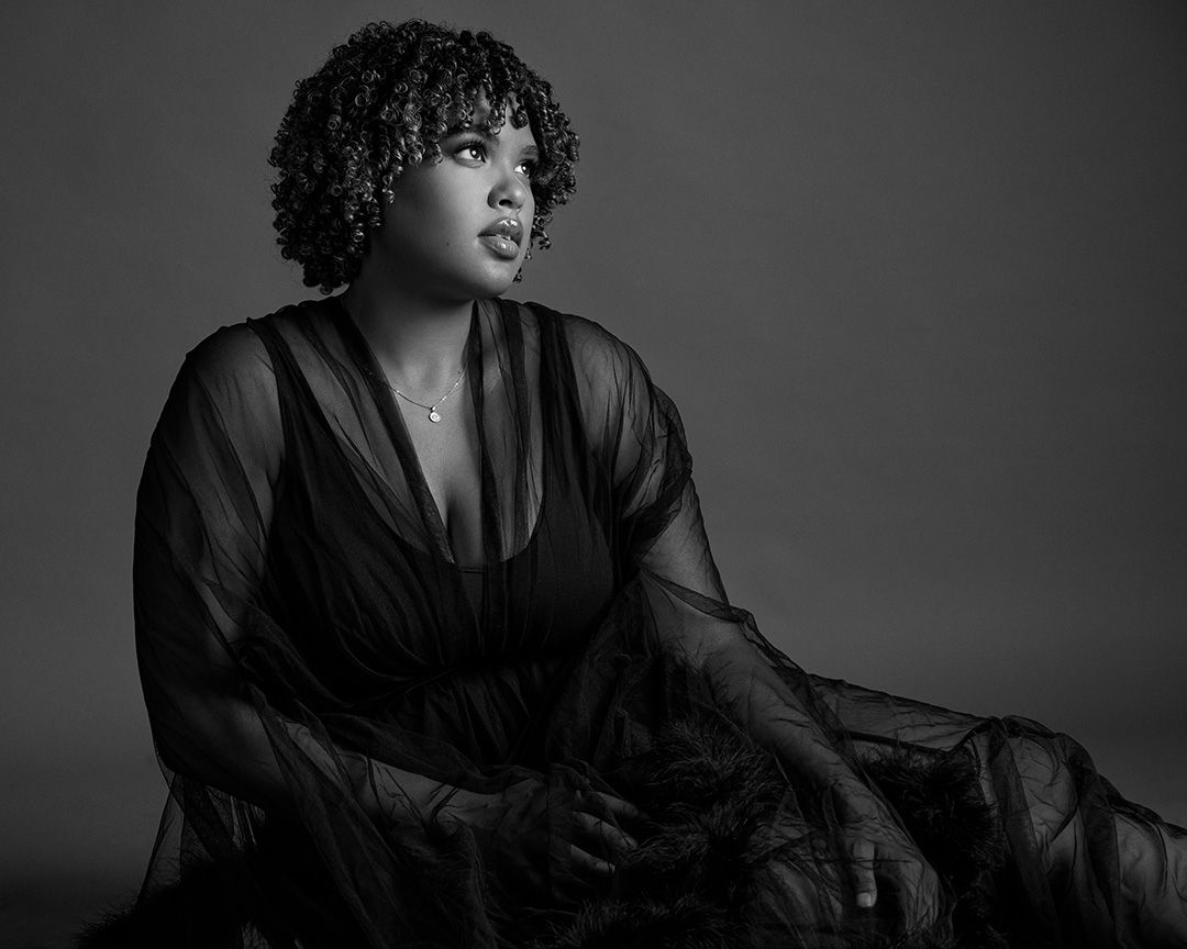 Artistic black and white portrait in sheer fabric against dramatic lighting.