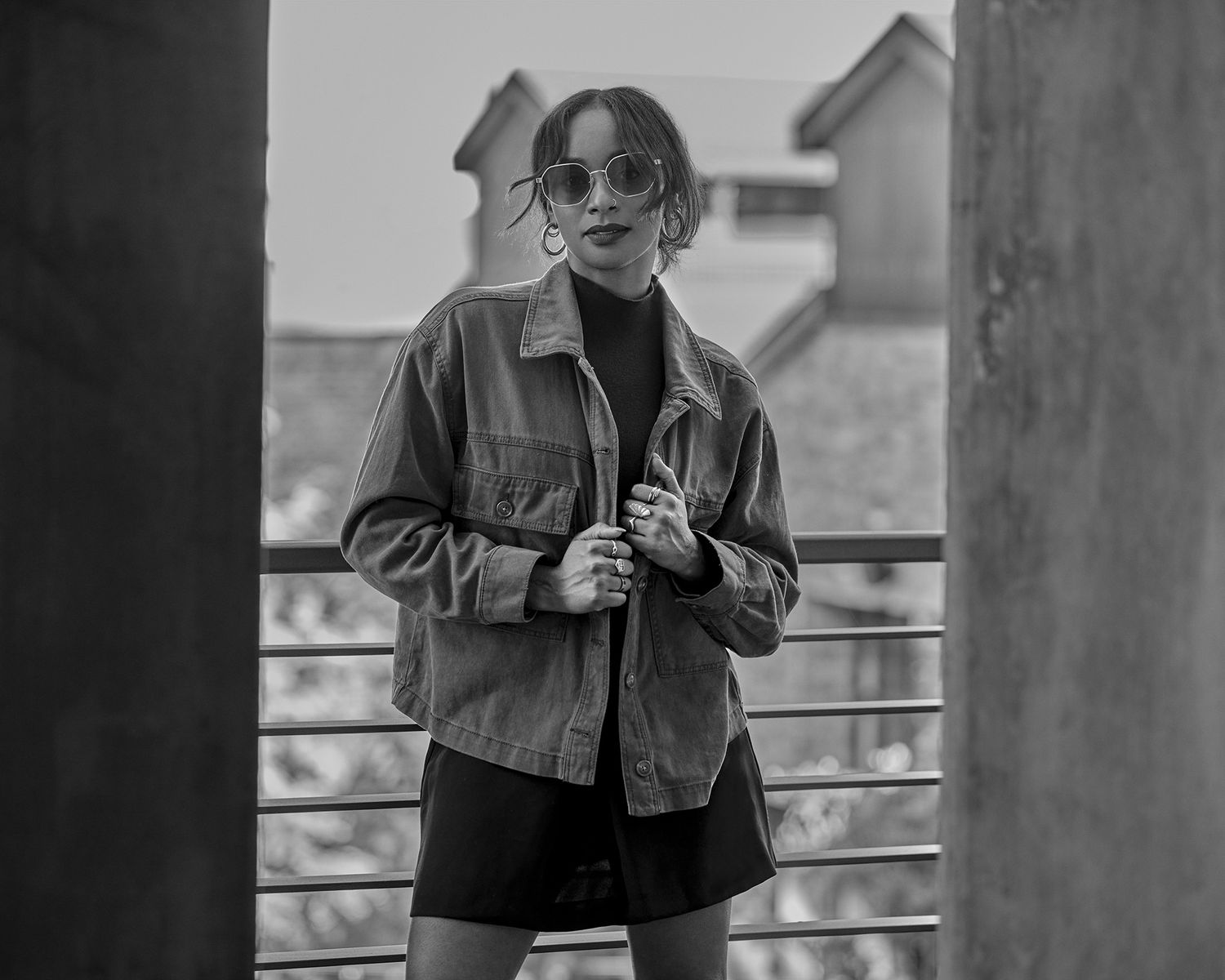 Street style portrait in denim jacket and sunglasses against urban architecture.