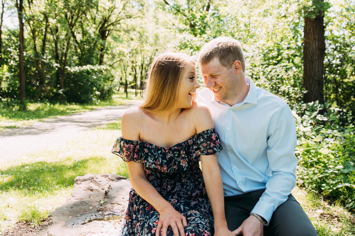 Happy engaged couple smile for portraits in the woods.