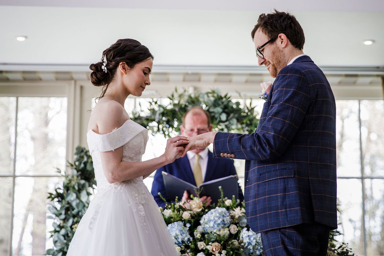 Bride and groom exchange rings during wedding ceremony at Kelham House