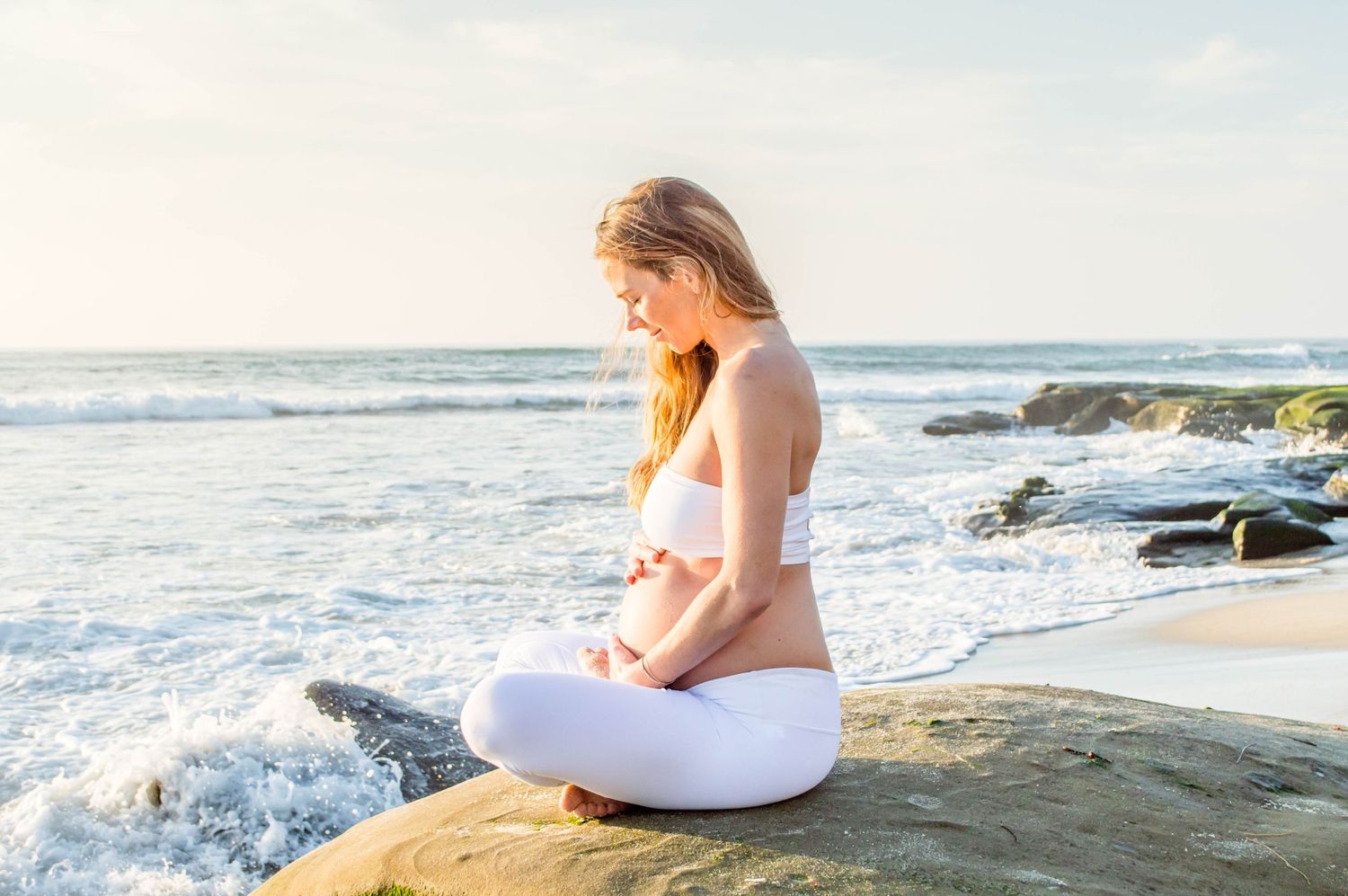 Peaceful meditation scene on rocky beach at sunset.