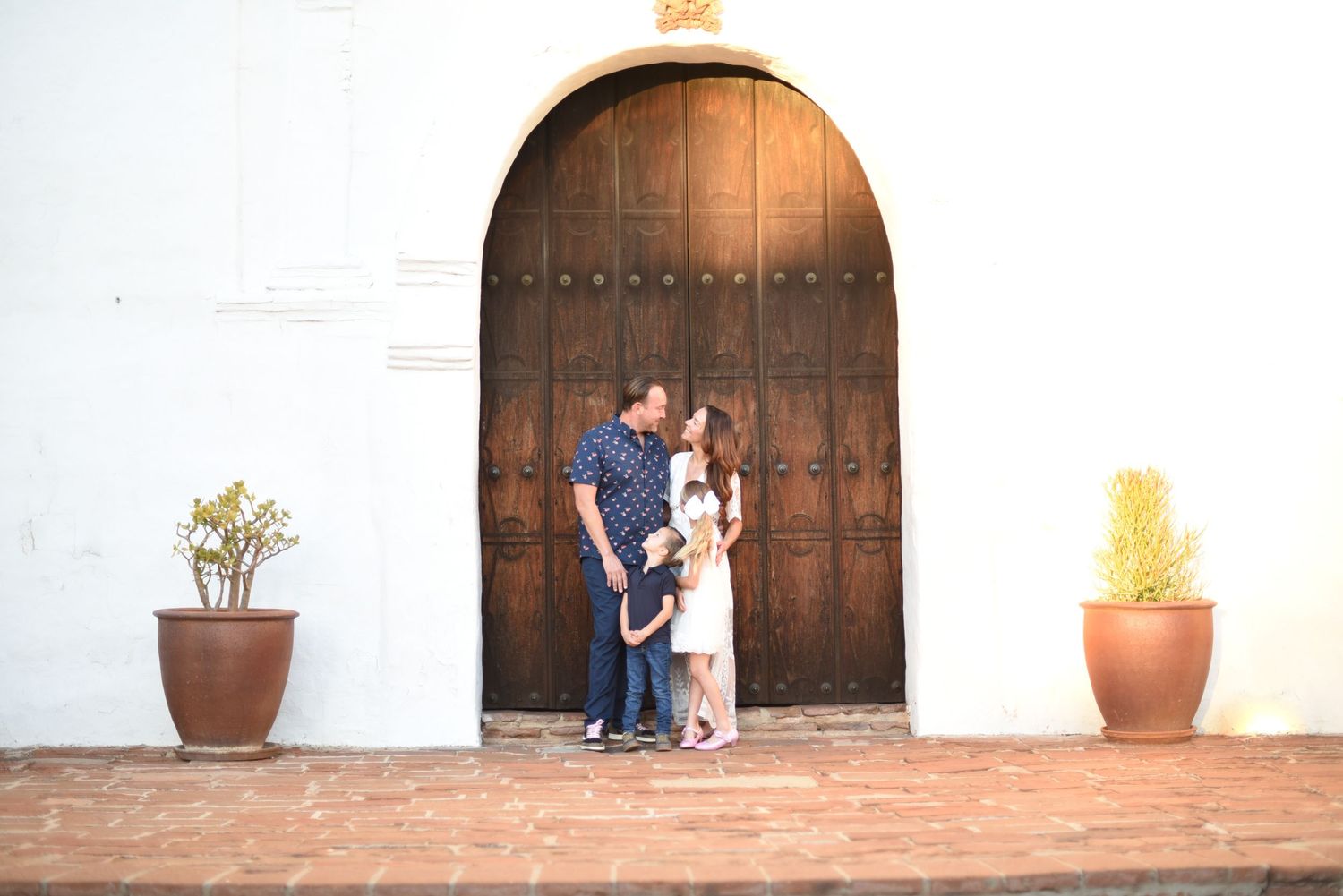 Engagement photos at Spanish-style mission with rustic wooden doors and terracotta pots.