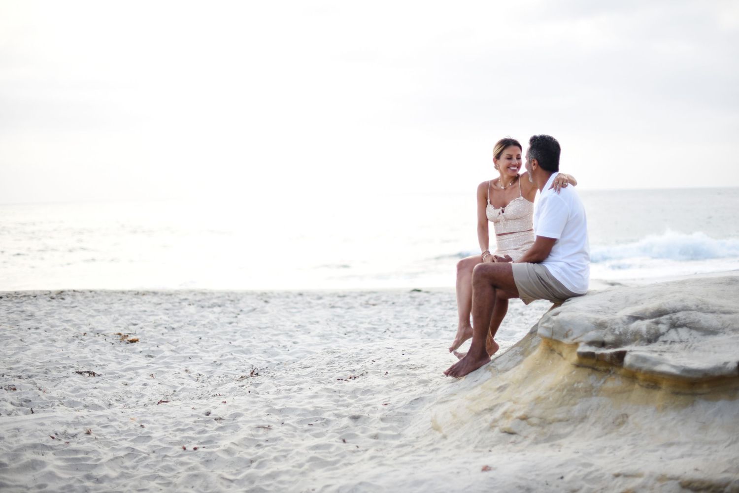 Candid family moments captured on sandy beach with crashing waves at golden hour.