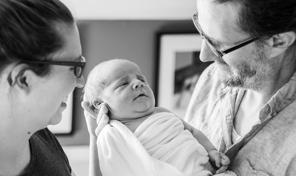 Black and white candid moment of new parents gazing at their newborn.