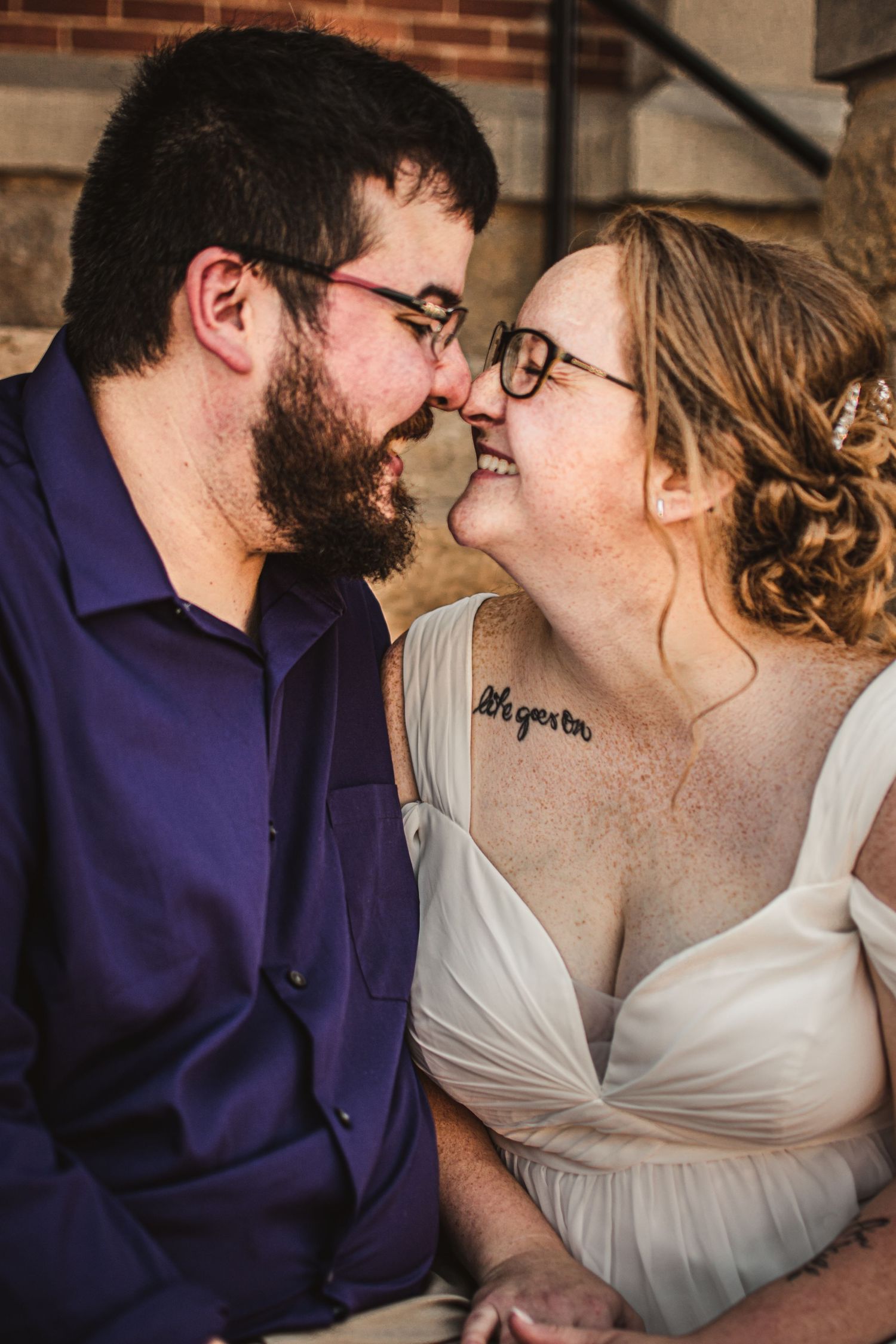 Intimate moment shared between a couple in formal wear against a brick wall.