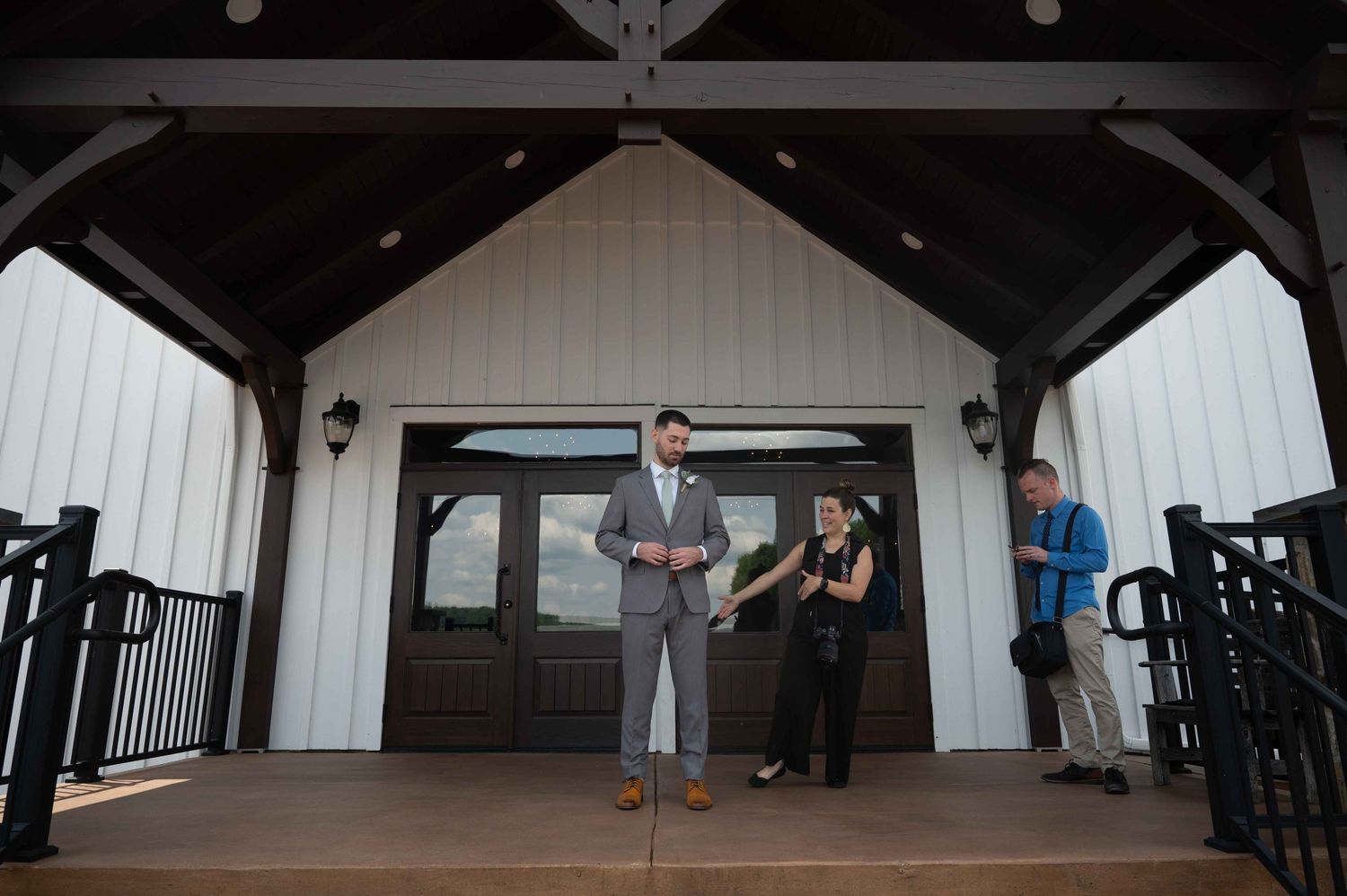 Wedding party members standing on a covered porch of a white building.