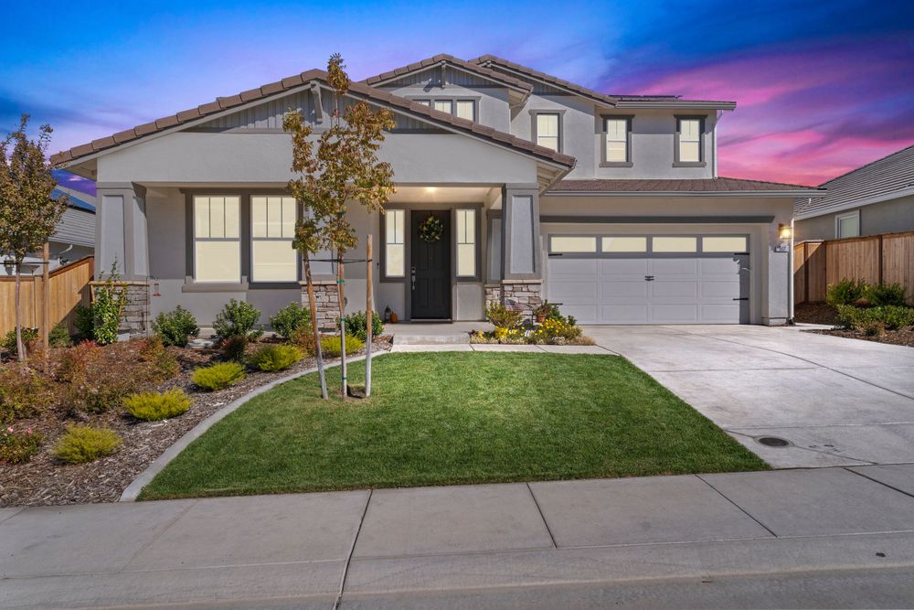 Suburban homes with well-maintained lawns and driveways captured during dramatic sunset.