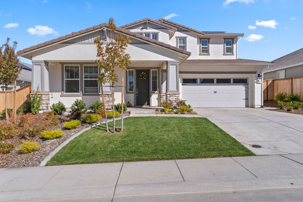 Modern residential homes with manicured lawns and concrete driveways under dramatic sky.