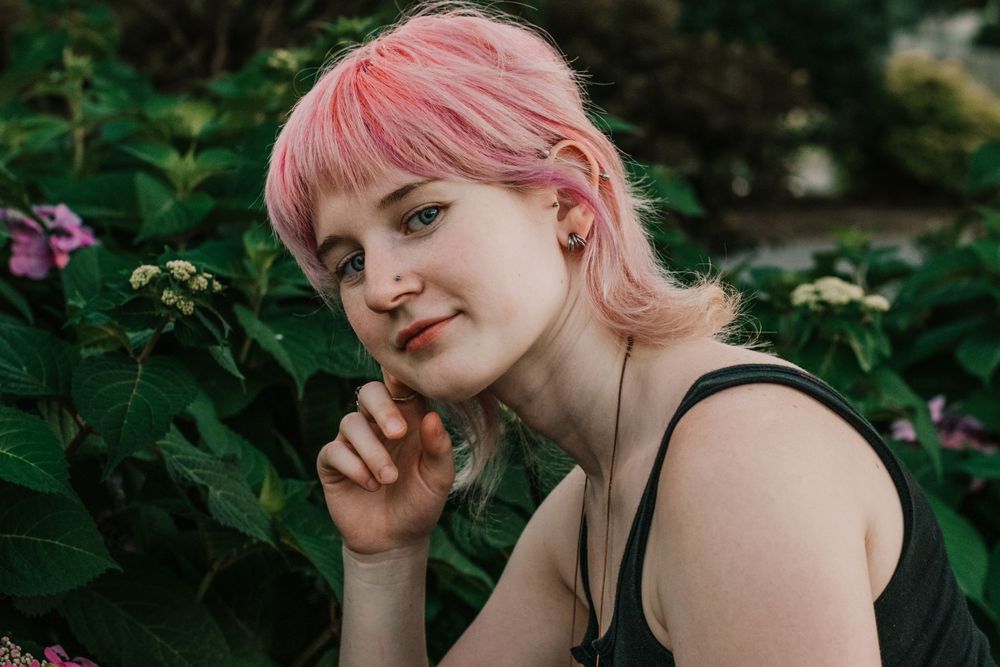 A young woman shares a knowing glance with the camera amidst lush greenery