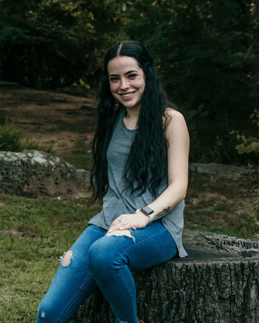 A young woman reclines joyfully on a tree stump