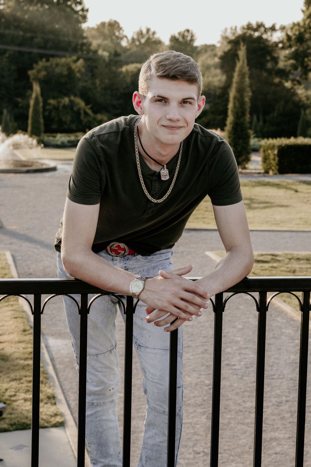A young man leaning against a fence for his senior photos