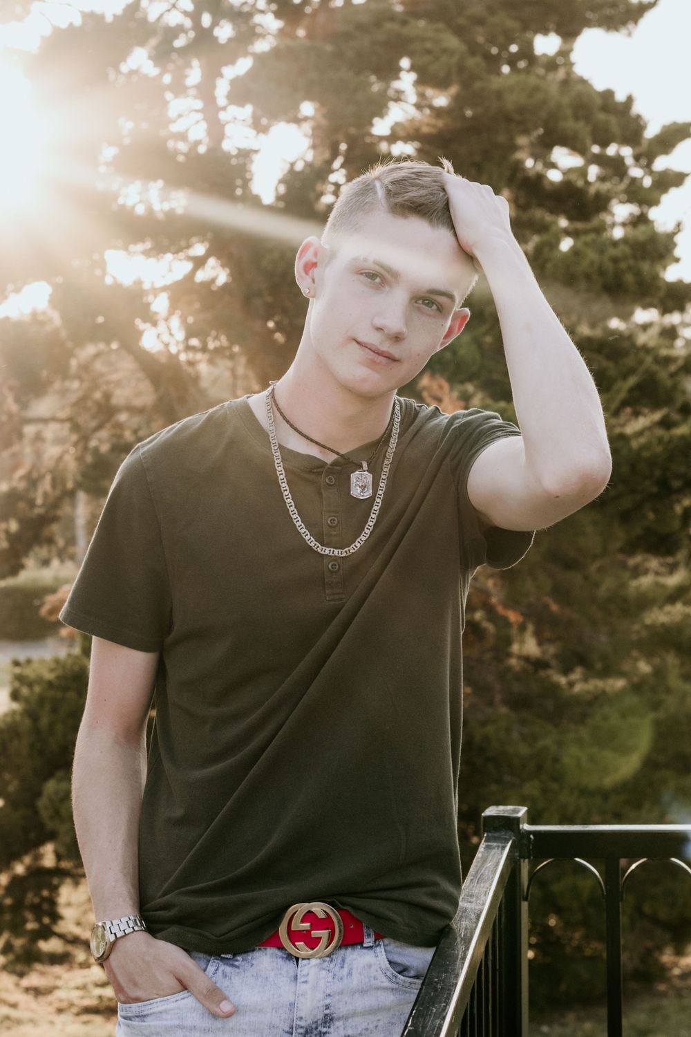 A young man running his fingers through his hair as he poses in front of a setting sun