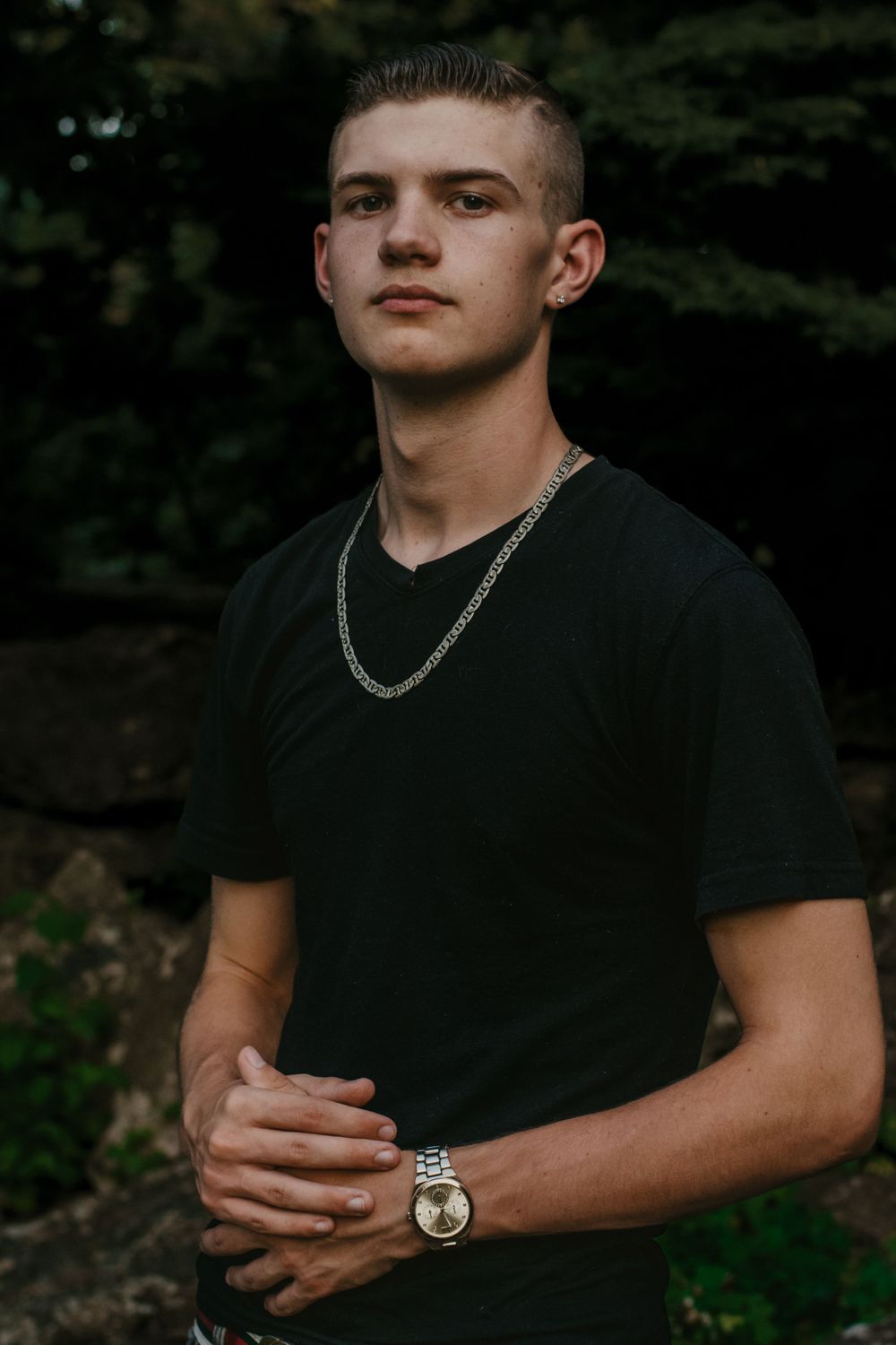 A young man poses confidently in a moody senior photo