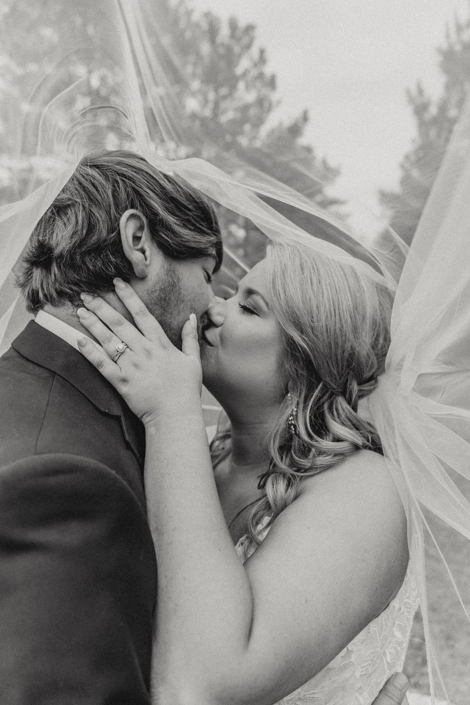 Black and white wedding portrait capturing intimate kiss between newlyweds.