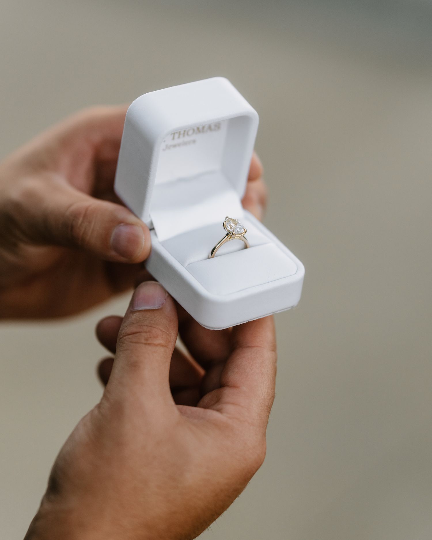 Elegant white ring box containing a sparkling engagement ring.