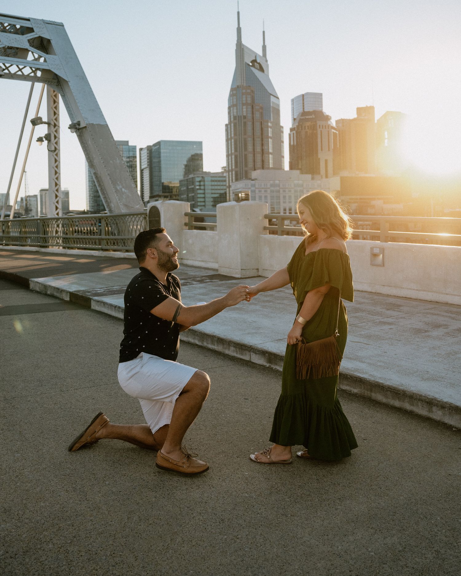 A romantic sunset proposal on a bridge in Nashville with the iconic AT&T building in the background.