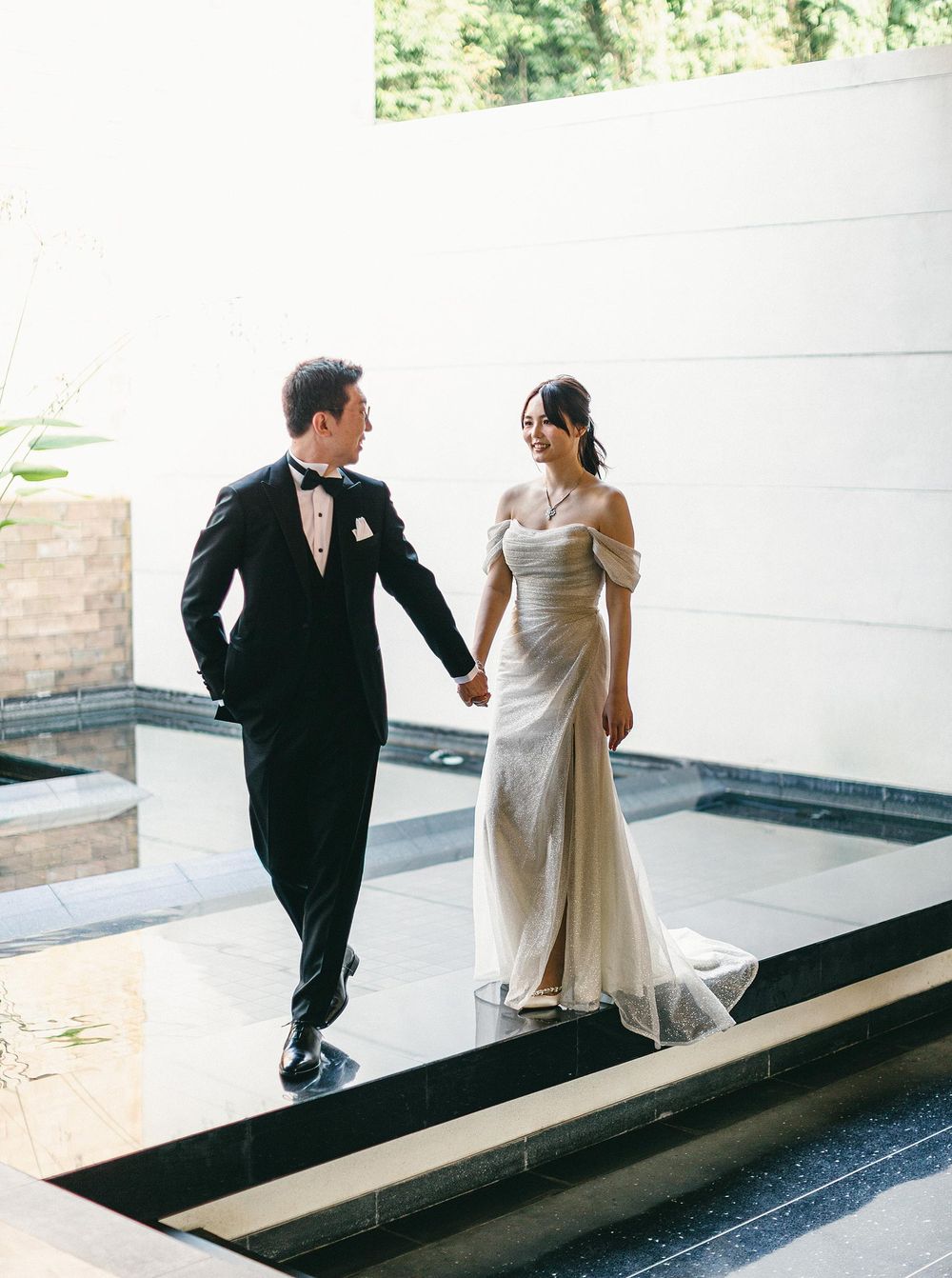 A bride and groom walk through a courtyard at their wedding in Phuket, Thailand.