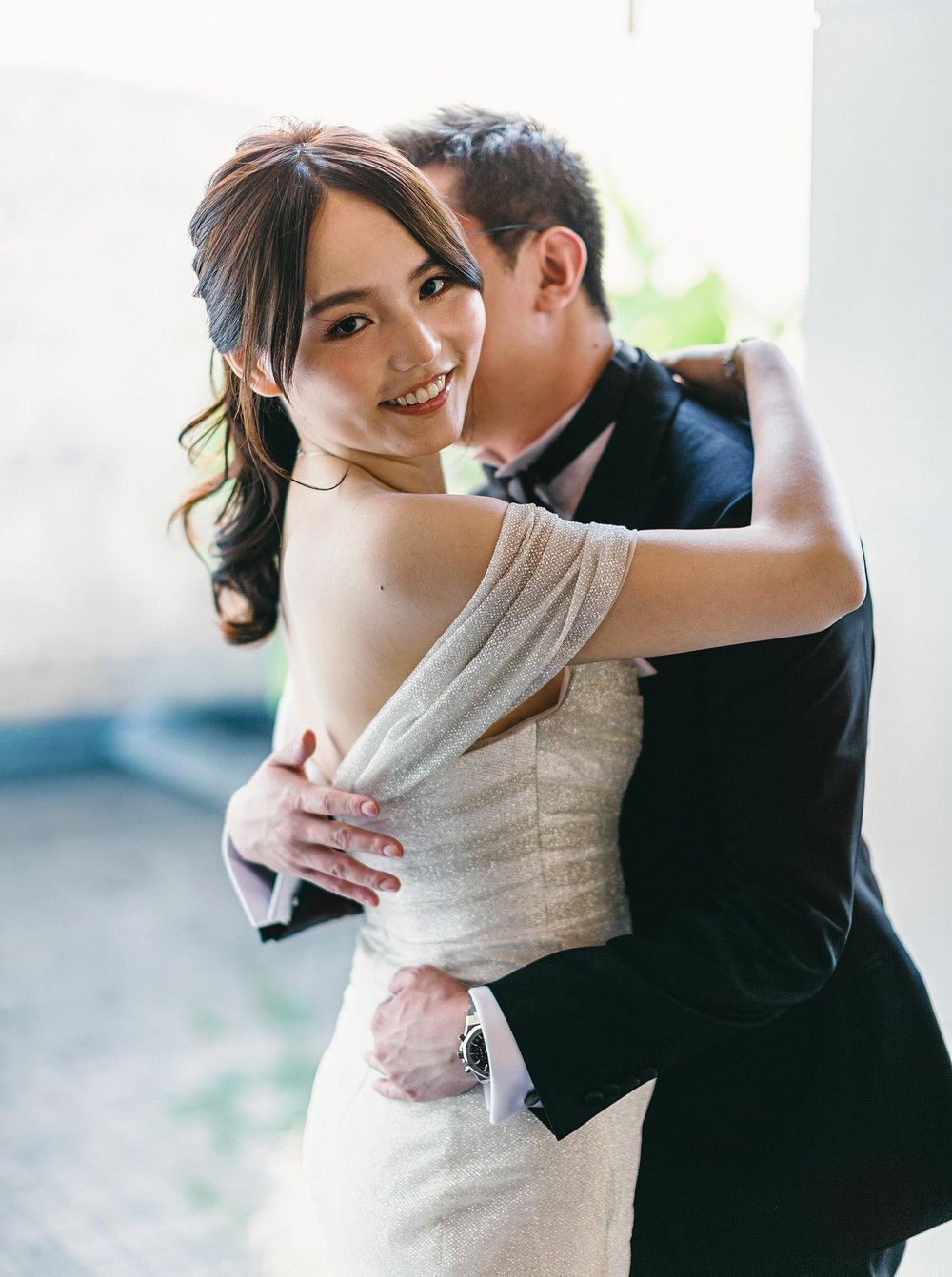 A bride and groom embrace in front of a building at Phuket, Thailand.