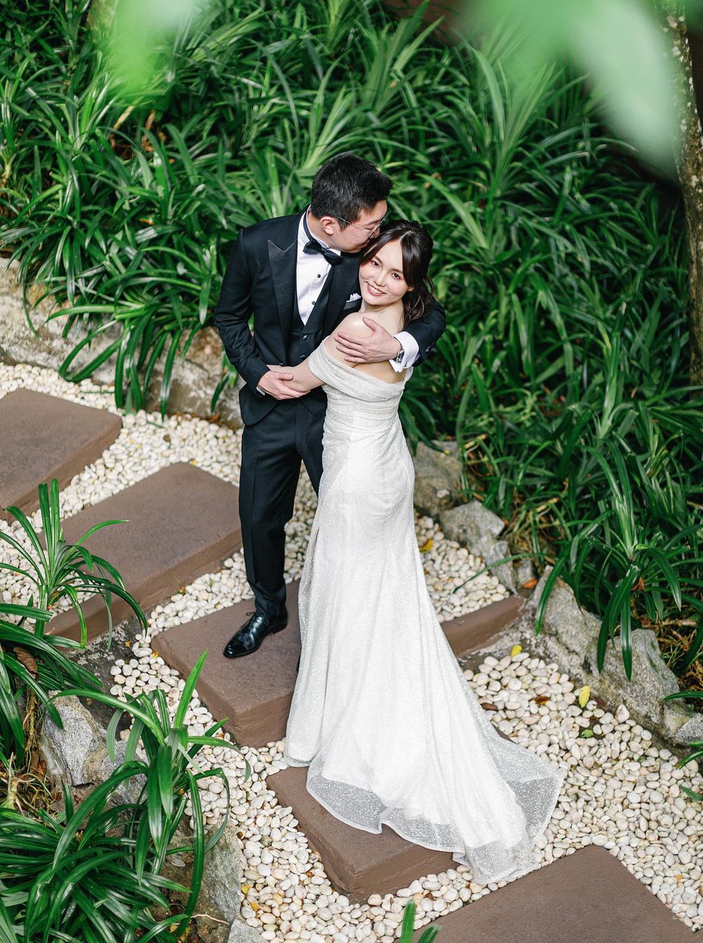 Wedding photographer capturing a beautiful romantic moment of a bride and groom in greenery of Phuket, Thailand.