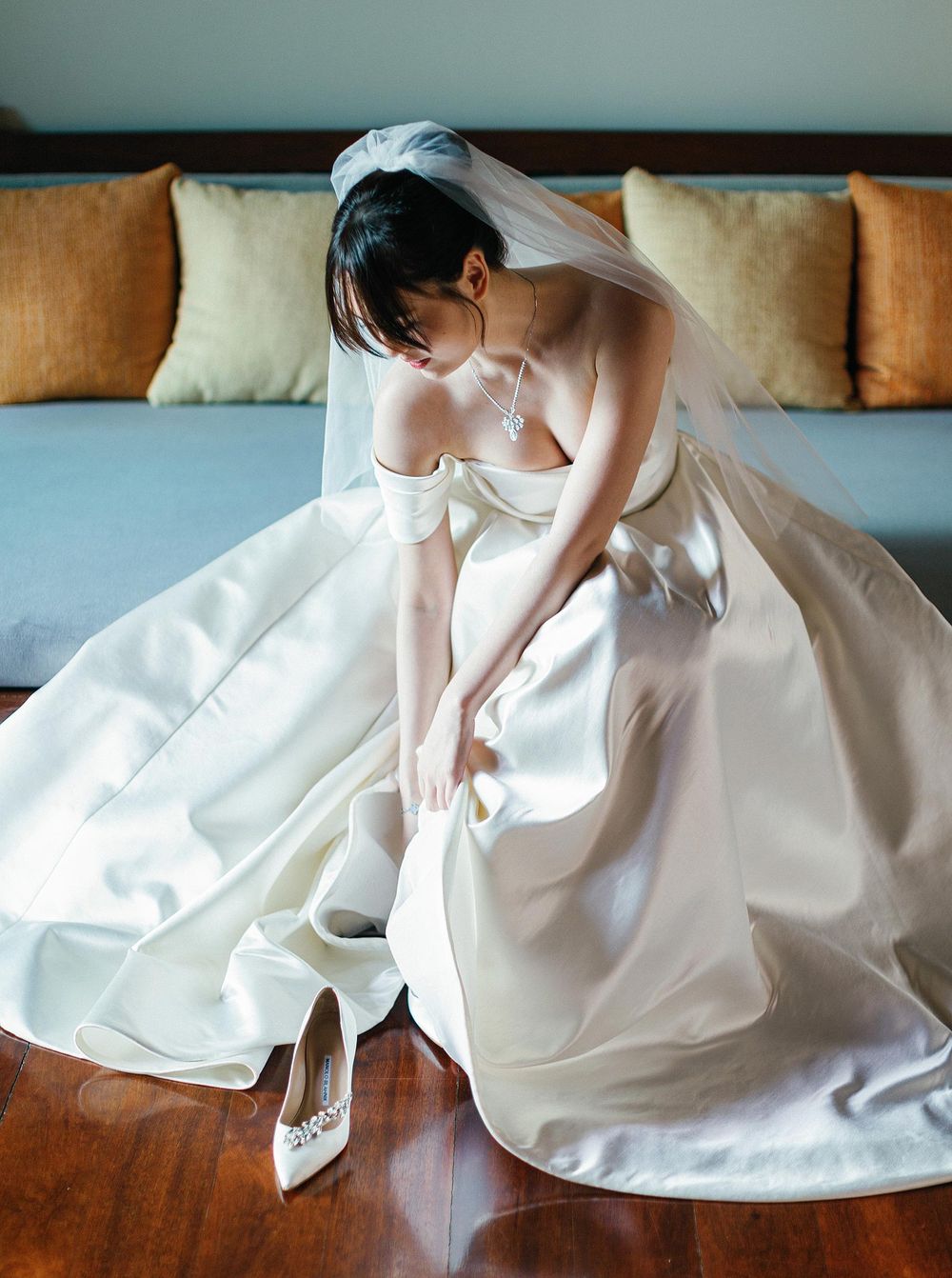 A bride in a wedding dress sitting on the floor, getting ready at Paresa Resort, Phuket, Thailand.