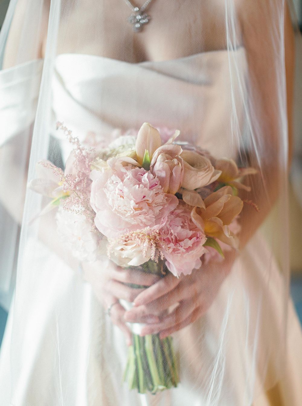 Bride in traditional wedding gown and veil, holding flowers in Phuket, Thailand.