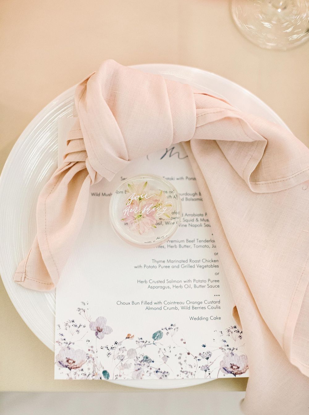 Wedding reception setup in Phuket, Thailand: pink napkin, white plate, and menu card.