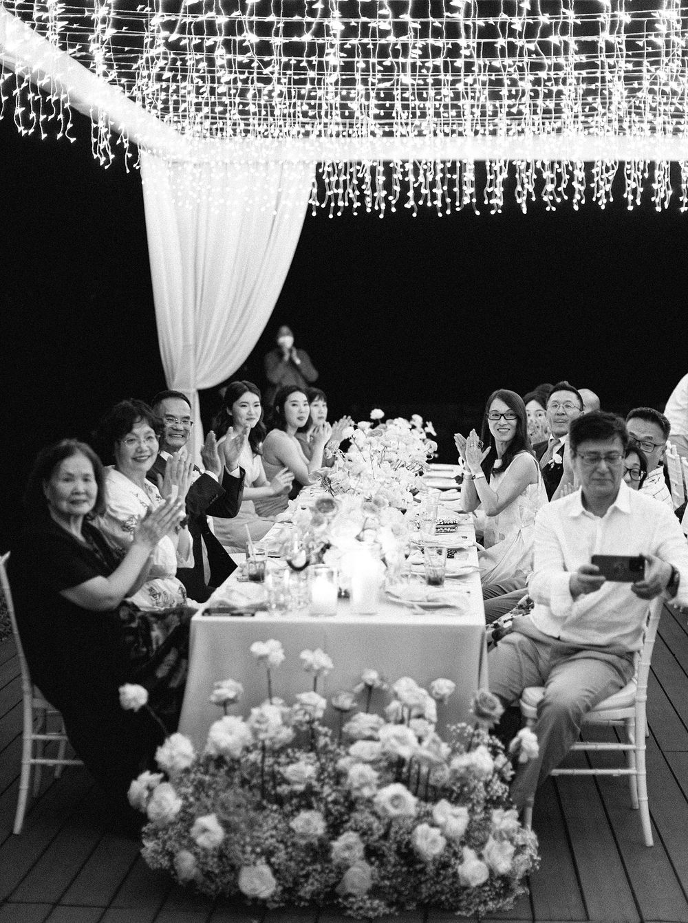Wedding guests seated at a table with decorative lights in Phuket, Thailand.