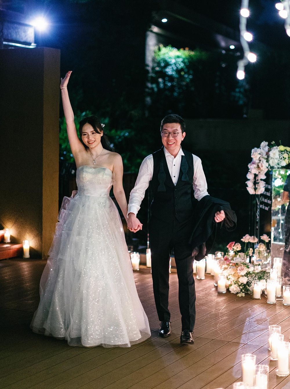 A bride and groom walk down the aisle at night during their entrance to a wedding reception in Phuket, Thailand.