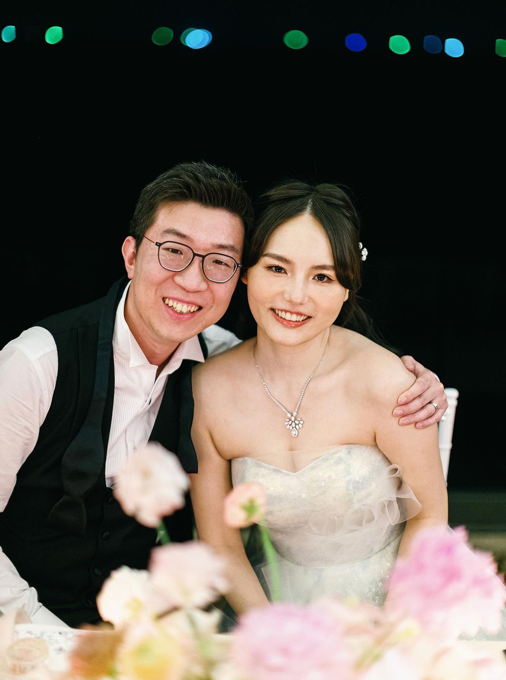 Newlyweds smiling for a picture at their wedding reception in Phuket, Thailand.