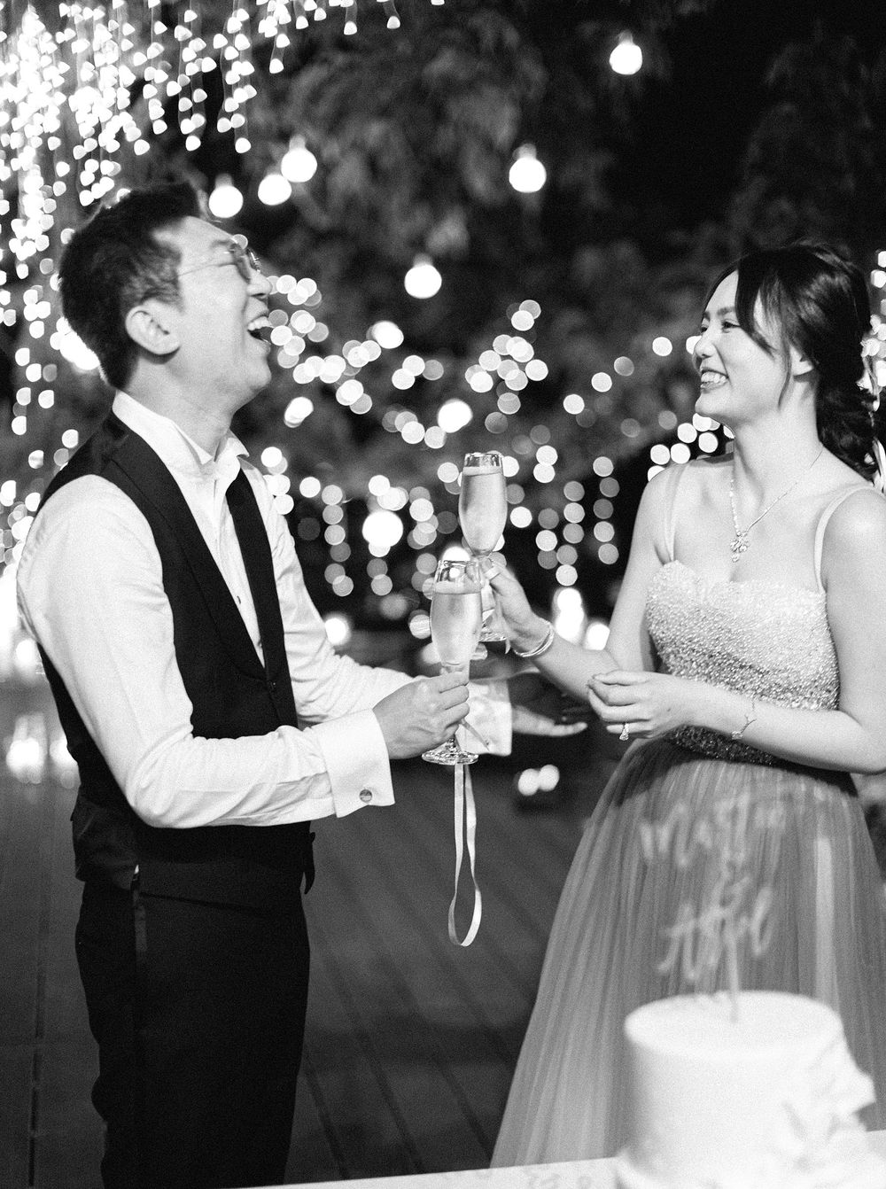 A bride and groom cheerfully toast each other under the night sky in Phuket, Thailand.