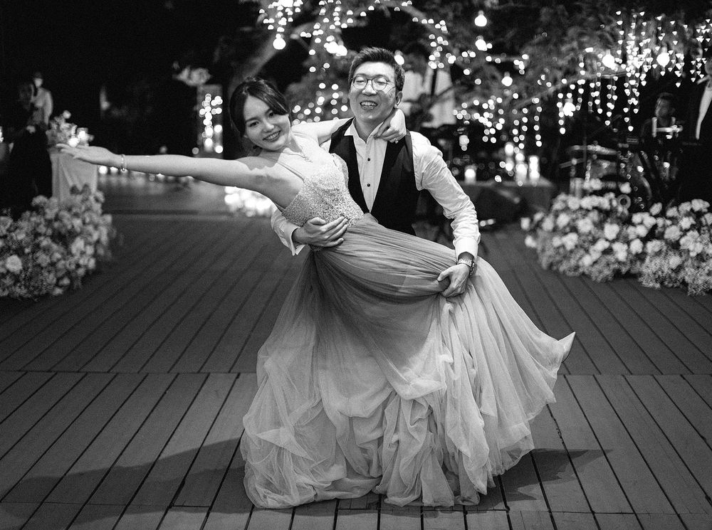 A newlywed couple gracefully dances on a wooden deck at night in Phuket, Thailand.