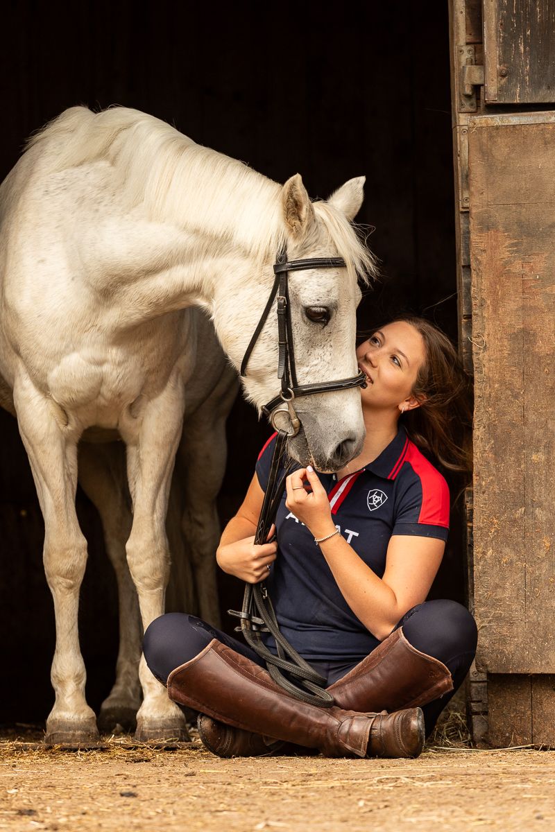 White horse and companion share a tender moment in a rustic stable setting.