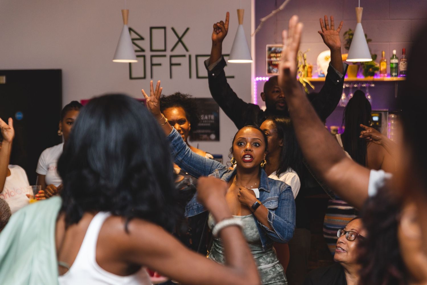 Energetic crowd dancing and celebrating at a party with arms raised.