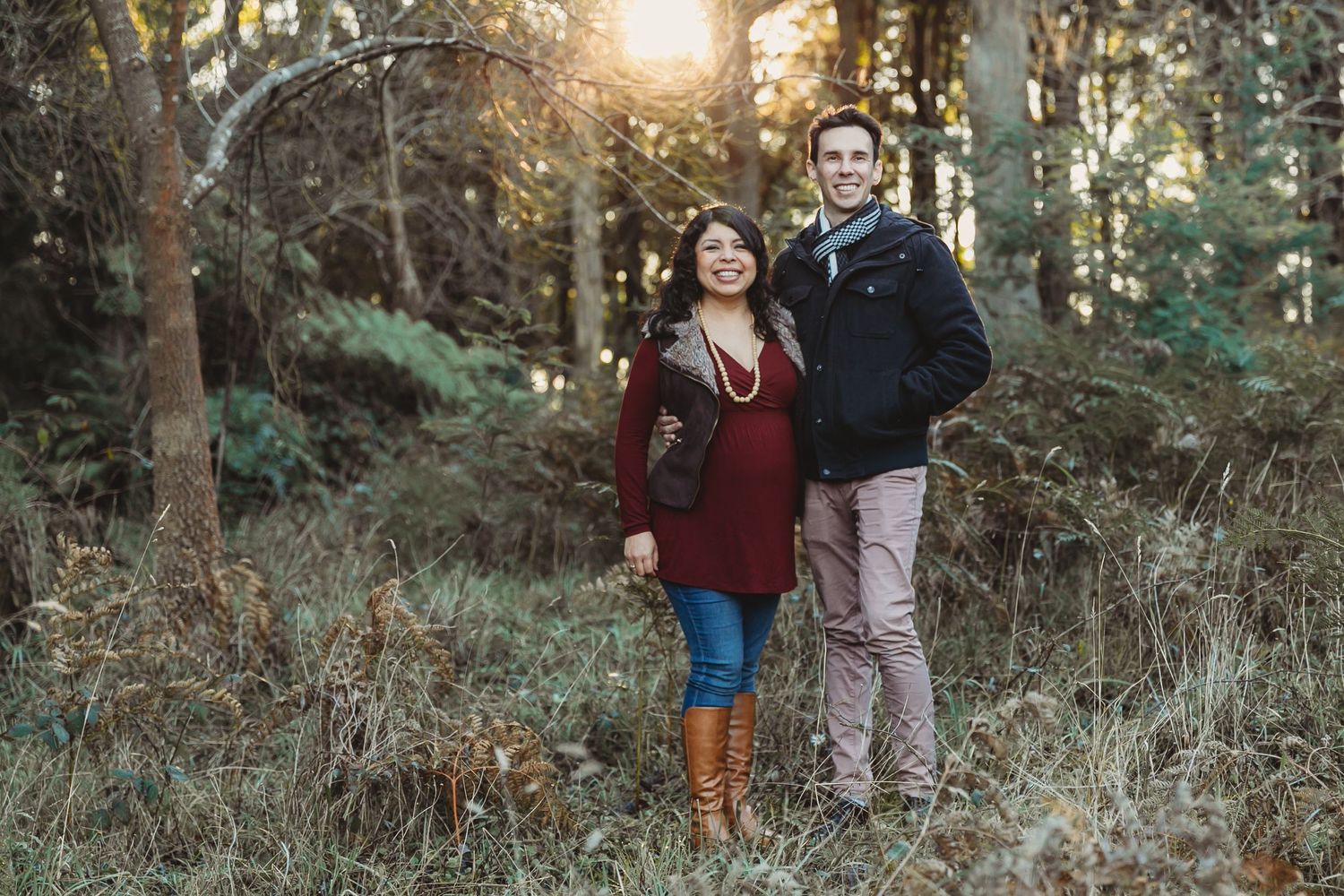 a couple expecting their first child, standing in the forest