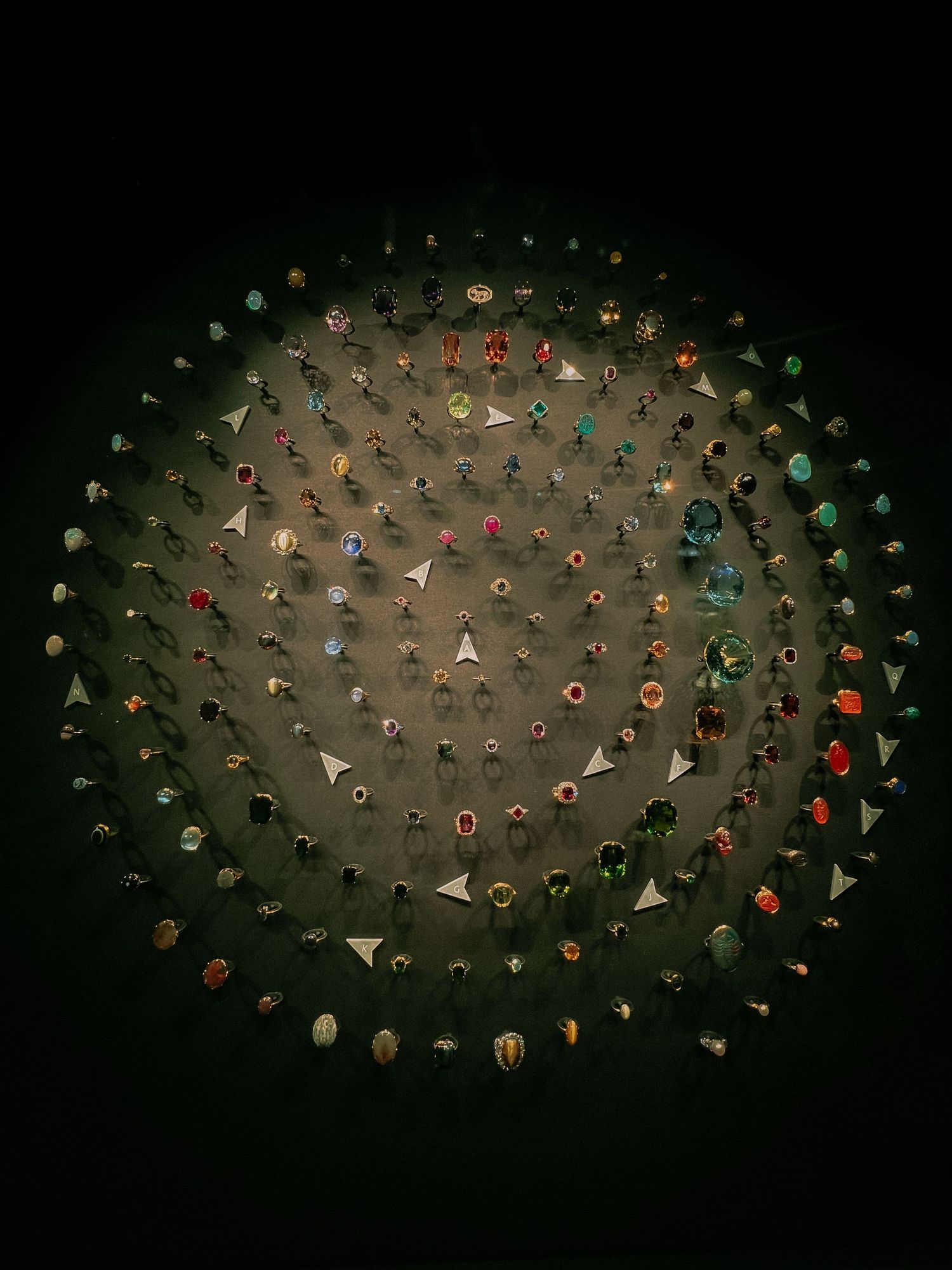 Aerial view of people arranged in spiral pattern formation on dark background.