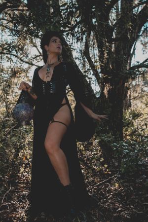 Atmospheric forest photoshoot with figures posed among trees and dappled sunlight.