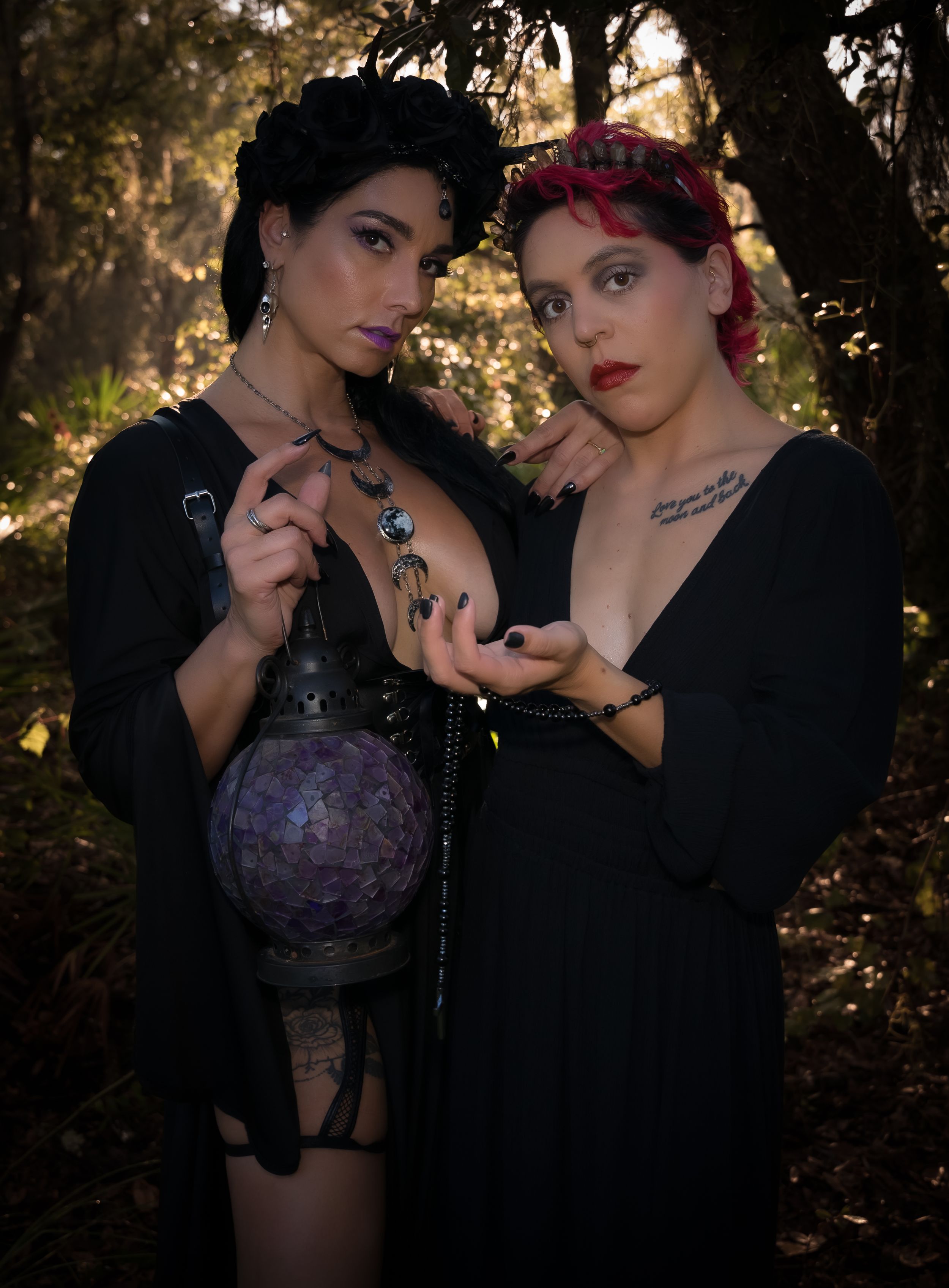 Two figures in dark clothing pose mysteriously in a woodland setting.