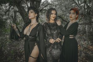 Gothic fashion shoot in a wooded setting featuring dark dresses and dramatic poses.